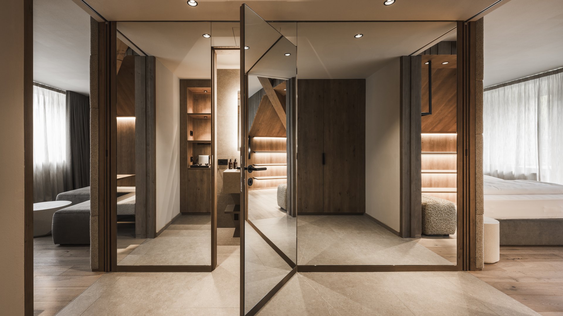 Wohnen am Kronplatz: Hotel an der Piste Moderner Raum mit geöffnetem Spiegel-Drehflügeltür und Holzverkleidung