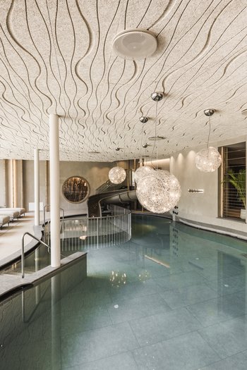 Il vostro hotel con spa tra le Dolomiti dell’Alto Adige Piscina interna moderna con lettini e lampade sospese decorative