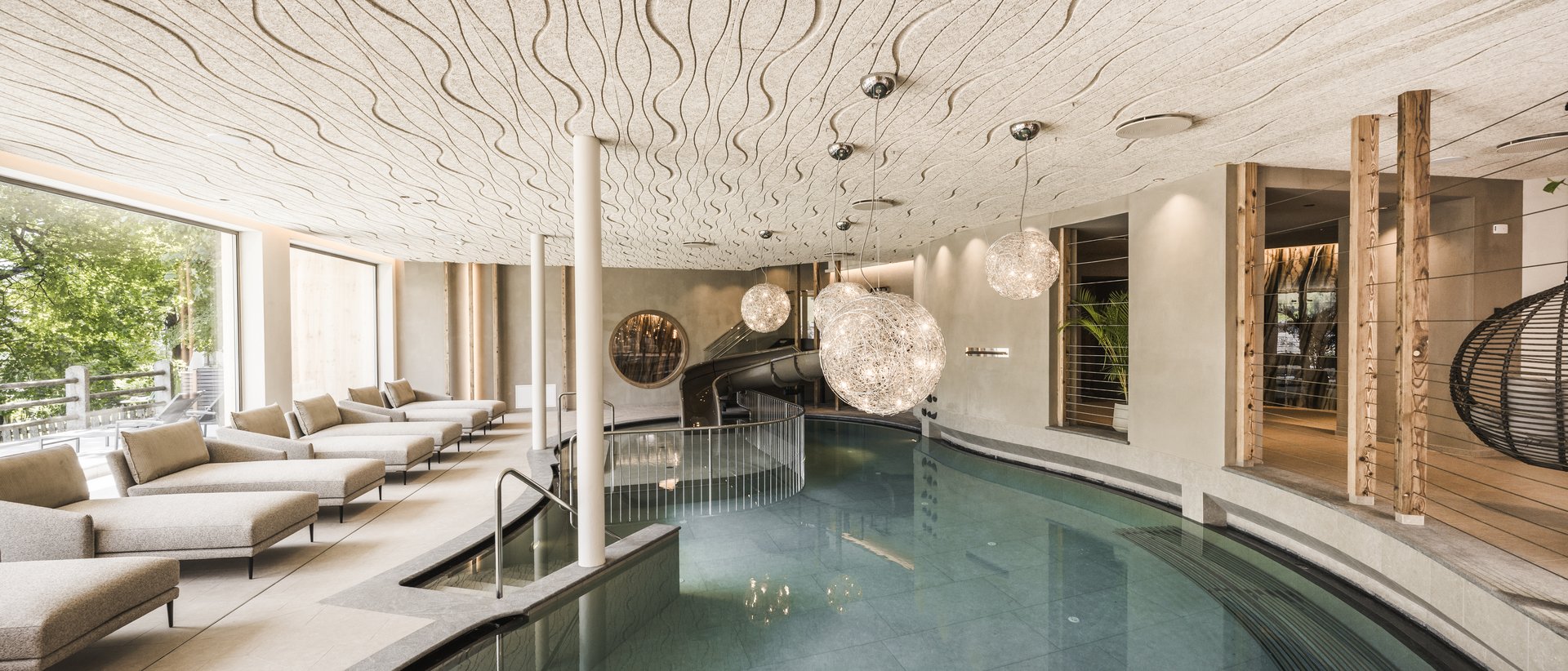 Le nostre novità 2024 Piscina interna moderna con lettini e lampade sospese decorative