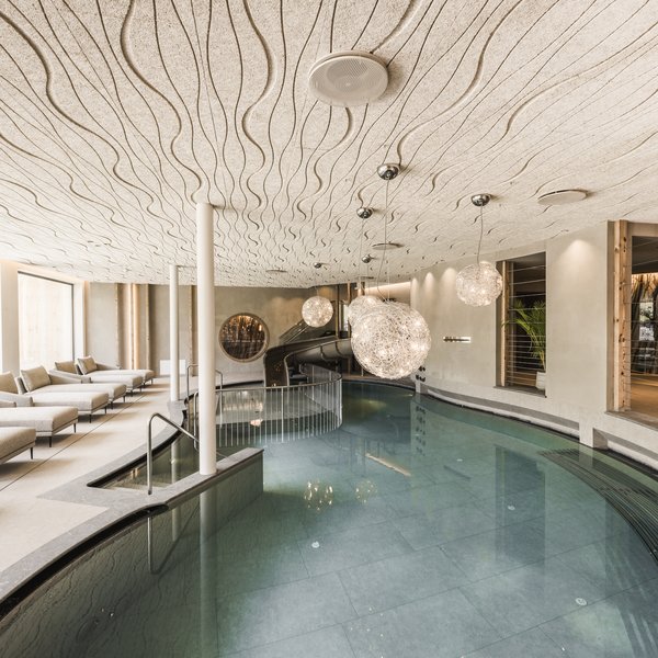 Dolomiten-Hotel für Bergmenschen Moderner Innenpool mit Liegen und dekorativen Hängelampen