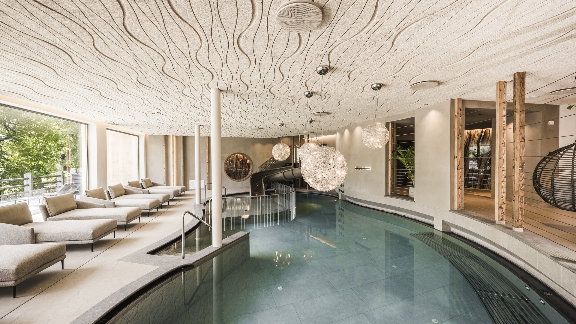 Excelsior: hotel wellness in Alto Adige per famiglie Piscina interna moderna con lettini e lampade sospese decorative