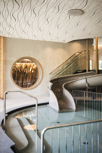 Family-friendly hotel in South Tyrol Modern water slide in indoor pool with wavy patterned ceiling