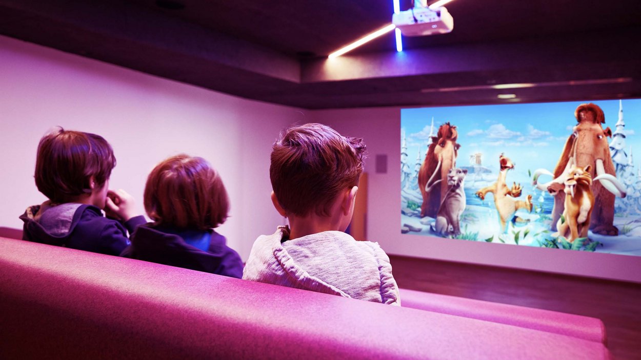 Family-friendly hotel in South Tyrol Children watching an animated movie in a home theater with pink seating
