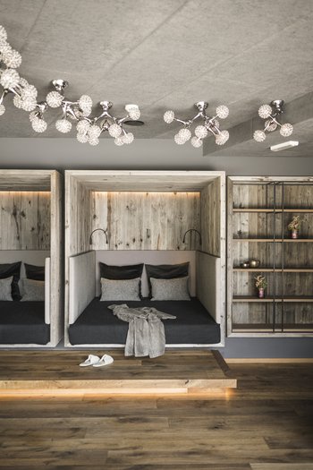 Hotel in the Dolomites for adults only Modern lounge bed with pillows, ceiling light fixture, and wooden shelf
