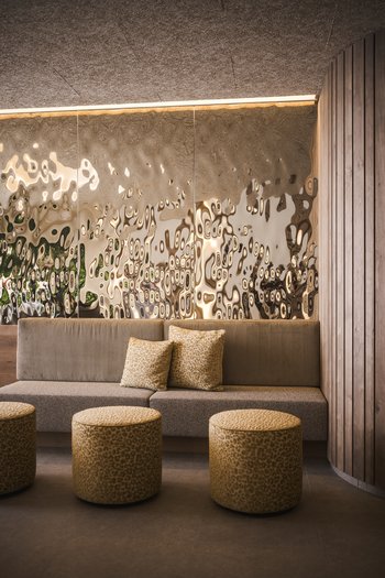 Hotel con infinity pool in Alto Adige: l’Excelsior Soggiorno moderno con divano, pouf e parete decorativa specchiata