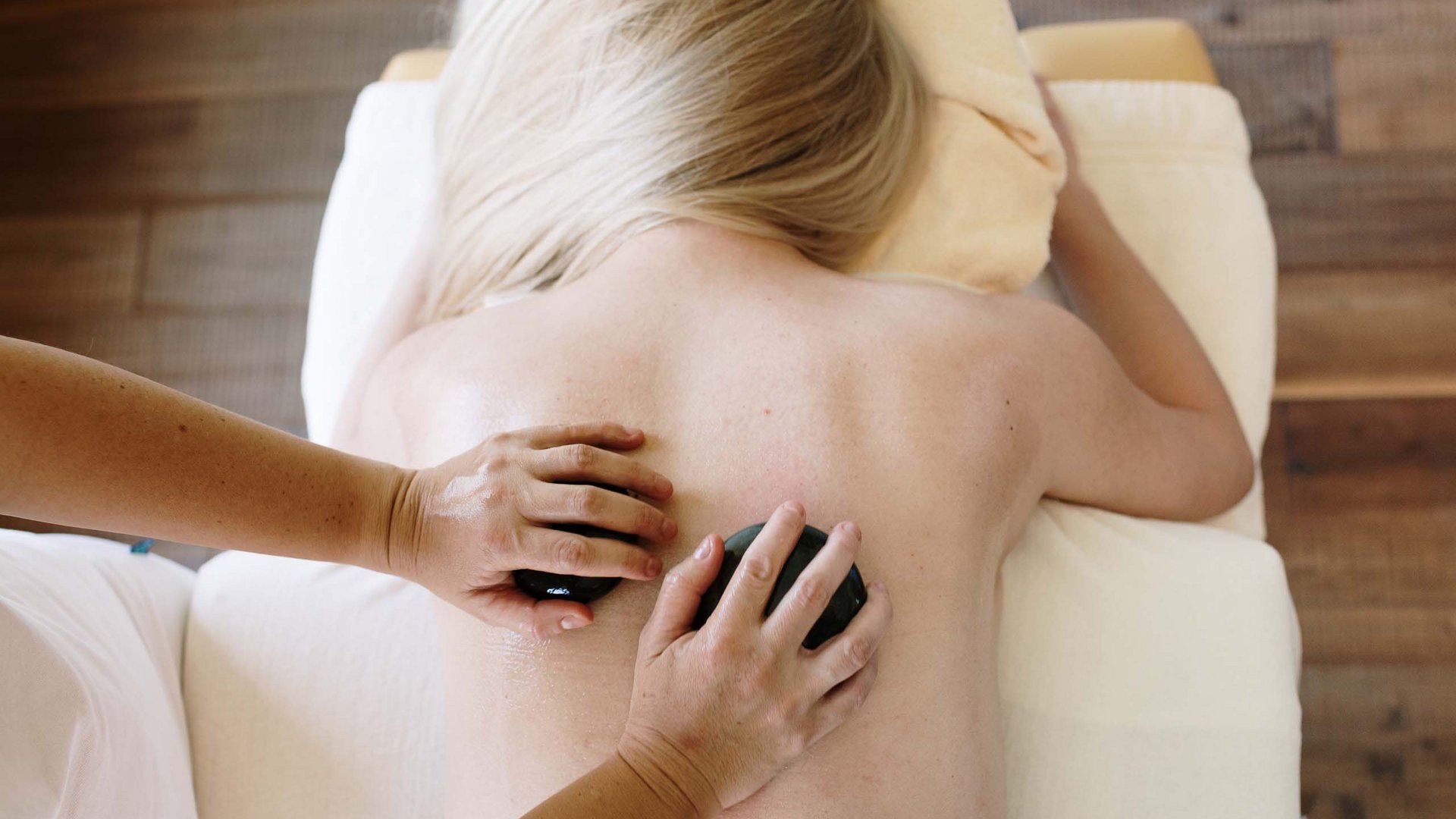 Wellnessurlaub | Dolomiten: Rückenfit® Frau erhält Hot-Stone-Massage auf Rücken in entspannter Atmosphäre