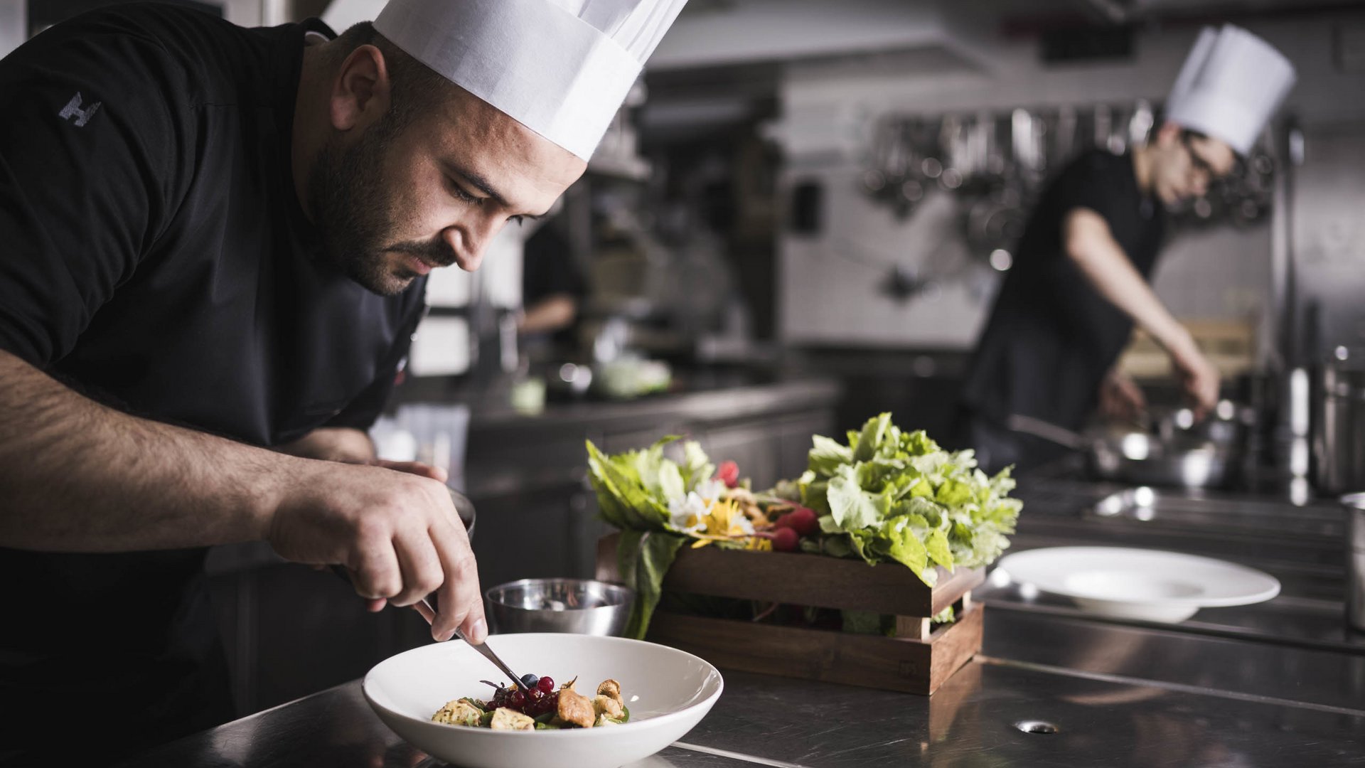 Sustainable hotels in South Tyrol? The Excelsior! Chef garnishing a dish in a professional restaurant kitchen