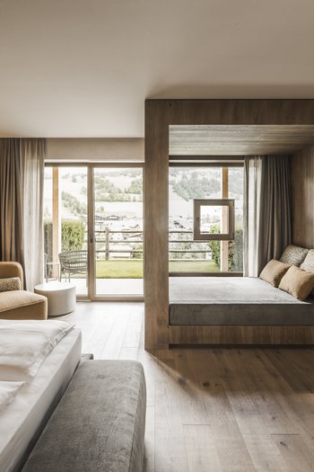 Le nostre novità 2024 Camera d'hotel moderna con dettagli in legno, ampie finestre e area salotto accogliente