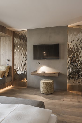 Unsere News 2024 Modernes Hotelzimmer mit Holzdetails, Fernseher und gemütlicher Sitznische