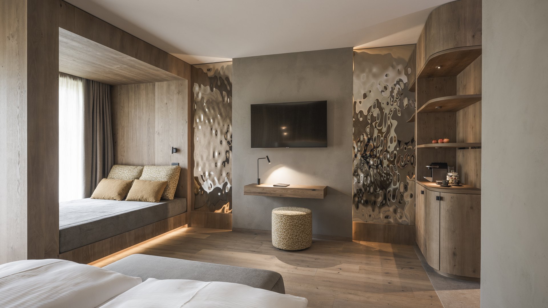 Ihr Hotel in St. Vigil in Enneberg! Modernes Hotelzimmer mit Holzdetails, Fernseher und gemütlicher Sitznische