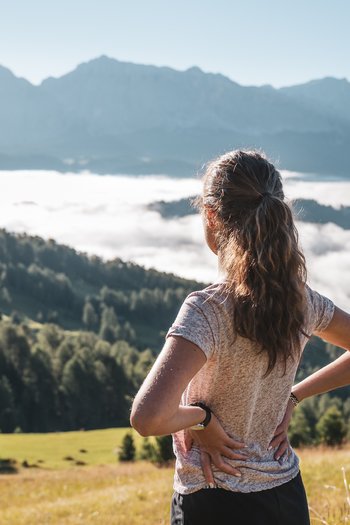 Excelsior: Wanderhotel in den Dolomiten Frau steht in den Bergen und blickt auf neblige Täler und Berggipfel