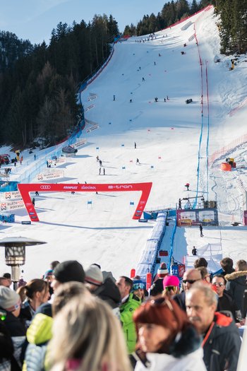 Around the hotel on the slopes in South Tyrol People watching a ski race on a snowy slope in sunny mountain area