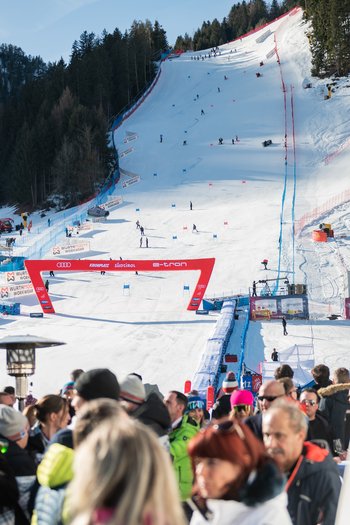 Around the hotel on the slopes in South Tyrol People watching a ski race on a snowy slope in sunny mountain area