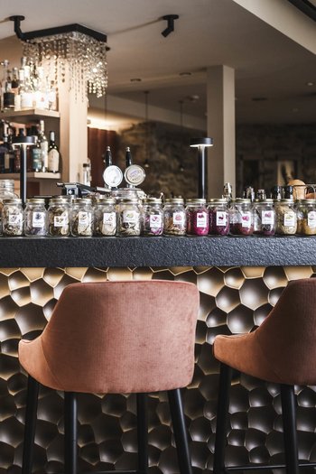 Molto più di un hotel a San Vigilio di Marebbe! Bar con sgabelli rosa e numerosi barattoli di spezie e erbe sul bancone