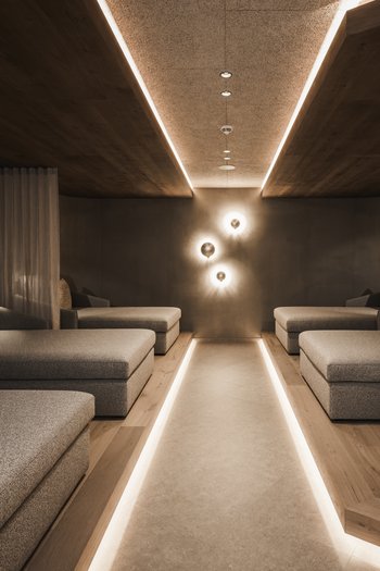 Hotel con infinity pool in Alto Adige: l’Excelsior Sala relax moderna con poltrone grigie e illuminazione indiretta