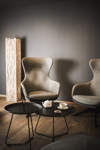 Wellness hotel in South Tyrol | Dolomites Cozy seating area with two armchairs, teapot, cup, and snacks on coffee table